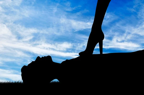 Силуэт феминистки ноги стоя на склоне мужчины — стоковое фото