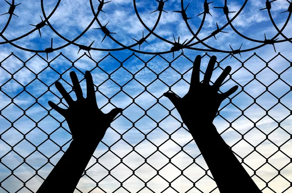 Руки біженця на прикордонному паркані — стокове фото