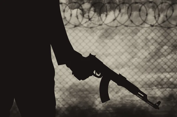 Silhouette of a terrorist near the fence of barbed wire — Stock Photo, Image