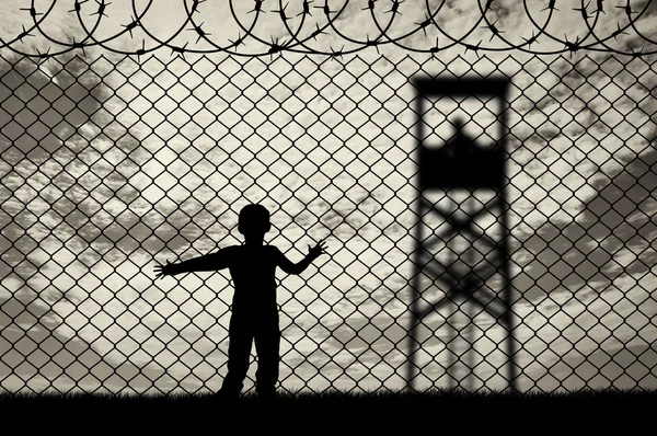 Kind vluchteling, in de buurt van het hek van prikkeldraad — Stockfoto