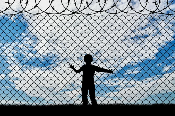 Niño refugiado, cerca de la cerca de alambre de púas — Foto de Stock