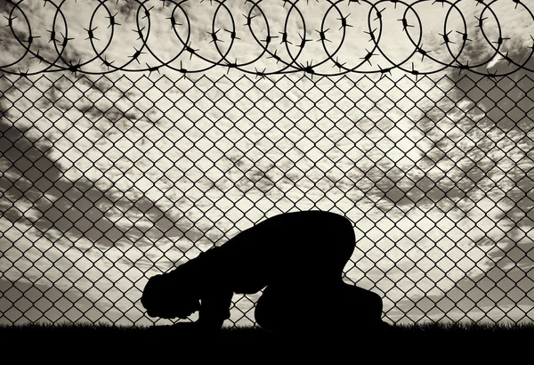 Muçulmano reza perto da cerca de arame farpado — Fotografia de Stock