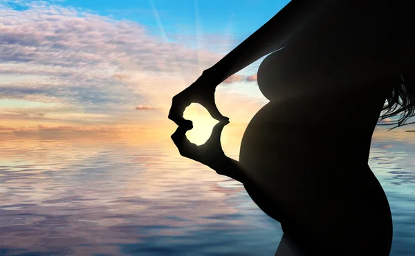 Pregnant woman shows her hands a heart symbol — Stock Photo, Image