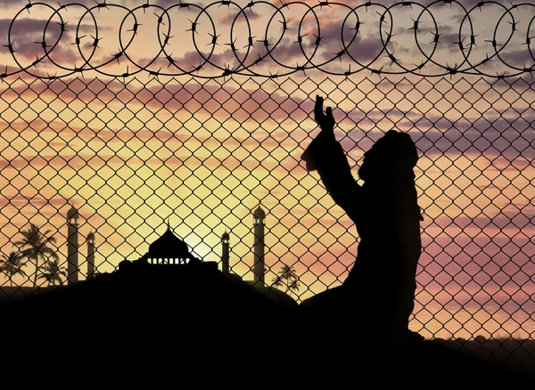 Moslim bidden in de buurt van het hek van prikkeldraad — Stockfoto