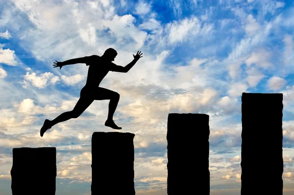 Running businessman jumps over cliffs — Stock Photo, Image