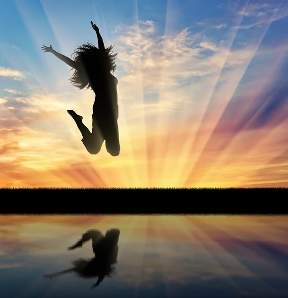 Щаслива жінка стрибає на заході сонця — стокове фото