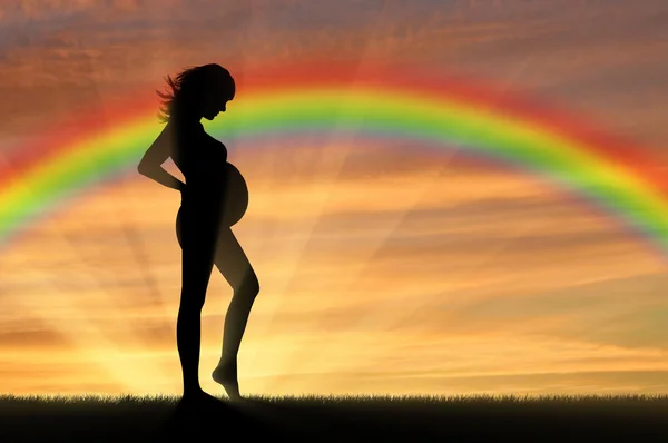 Беременная женщина на фоне радуги — стоковое фото