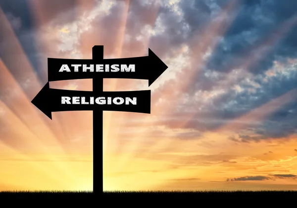 Road sign atheism and religion at sunset