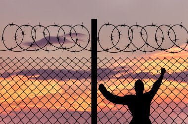 Siluet erkek mülteci ve dikenli tel çit