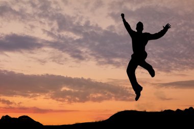 Günbatımında atlama bir adam silüeti