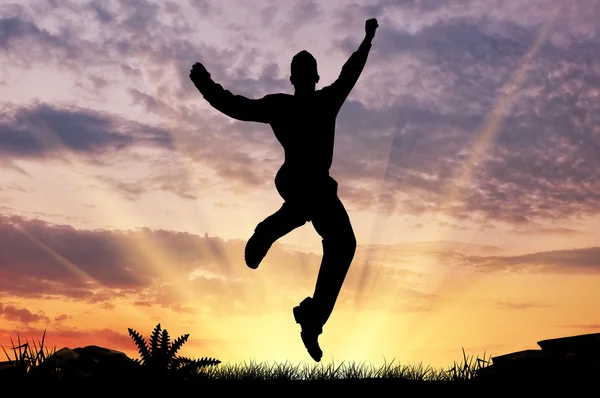 Silhuetten av en man som hoppar i solnedgången — Stockfoto