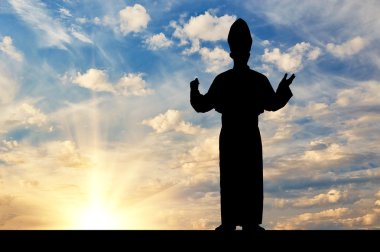 Silhouette of the Pope against the evening sky clipart