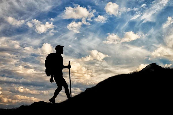Silhuetas de turista ascendendo a montanha ao pôr do sol — Fotografia de Stock