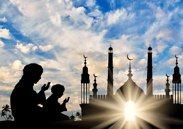 Silhouette of two men praying