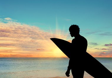 Sahildeki bir sörfçünün silueti.