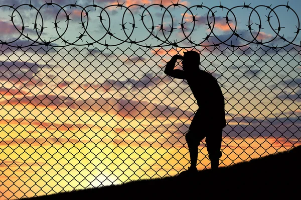 Silhouet van vluchtelingen in de buurt van de grens hek — Stockfoto