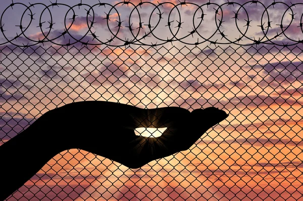 Sziluettjét menekült arms, közel a határ kerítés — Stock Fotó