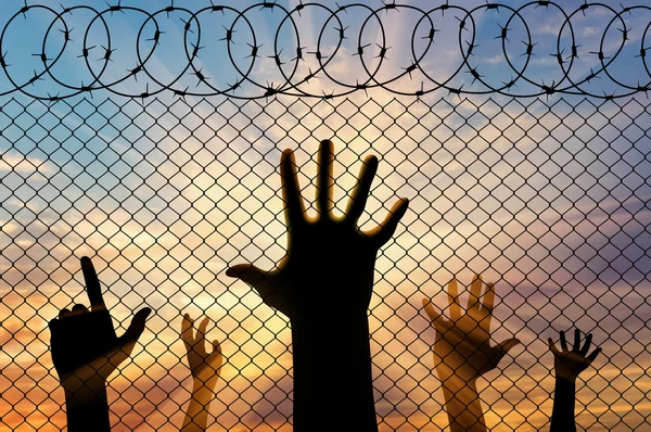 Силует біженців руки поблизу кордону паркан — стокове фото
