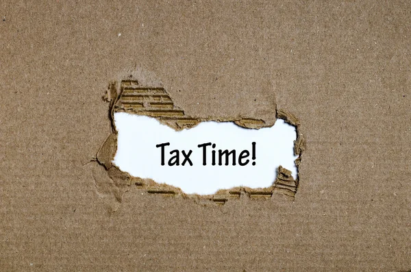 A palavra tempo de imposto que aparece atrás do papel rasgado — Fotografia de Stock