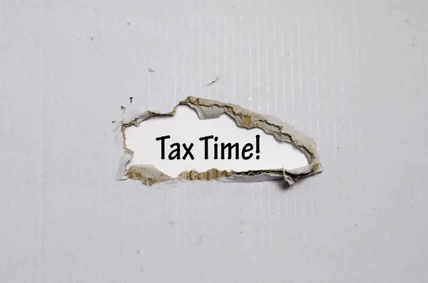 A palavra tempo de imposto que aparece atrás do papel rasgado — Fotografia de Stock