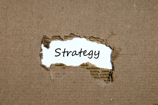 Het woord strategie verschijnt achter gescheurd papier — Stockfoto