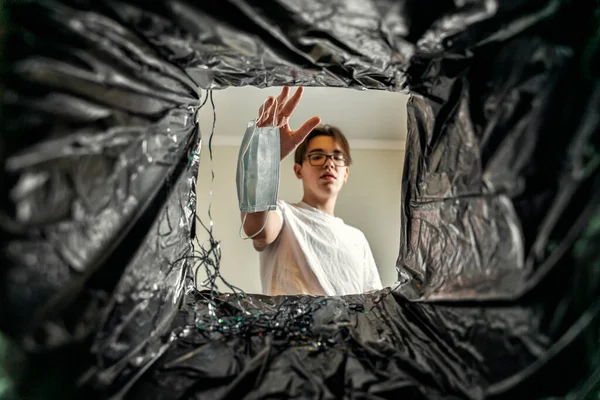 a man throws a disposable mask into the trash. view from the trash can