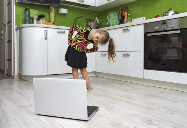 little girl with laptop doing gymnastics at home