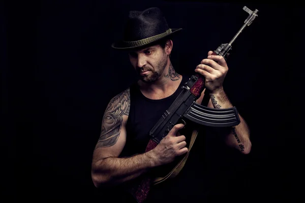 Low key portrait of gangster with hat and maschine gun in the da — Stock Photo, Image