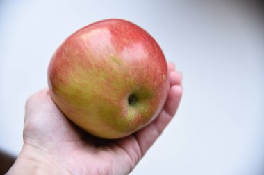 Elinde kırmızı elma var.