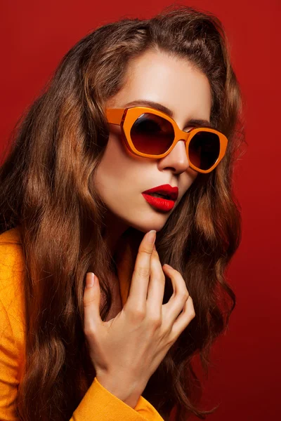 Model in de oranje jas en zonnebril — Stockfoto