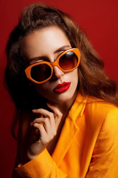 Model in de oranje jas en zonnebril — Stockfoto