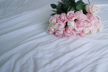 Beyaz bir çarşaf üzerinde pembe güller.