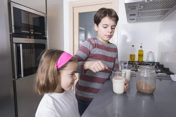 Children preparing a glass of milk — Stock Photo, Image