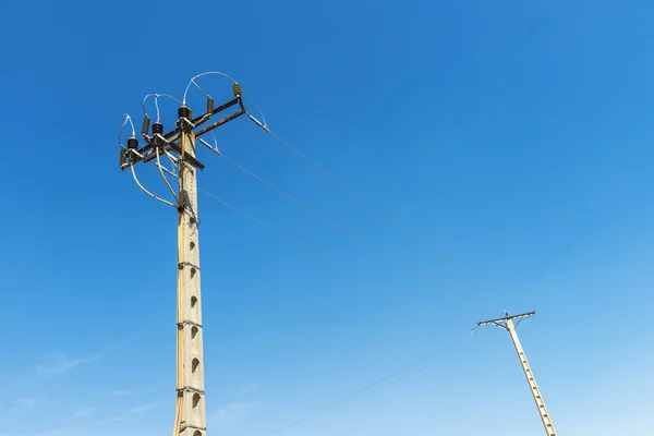 Dos postes de electricidad contra el cielo azul —  Fotos de Stock