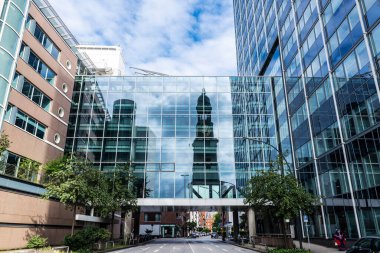 Hamburg, Almanya - 16 Ağustos 2019: St. Michael Kilisesi 'nin veya St. Michaelis' in çan kulesinin yansımasına sahip modern ofis binaları ve Neustadt, Hamburg, Almanya 'daki insanlar 