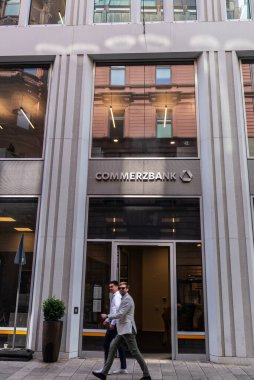 Hamburg, Almanya - 23 Ağustos 2019: Neustadt, Hamburg, Almanya 'da alışveriş caddesinde Grose Bleichen' de yürüyen iki genç adamla bir Ticaret Bankası şubesinin cephesi