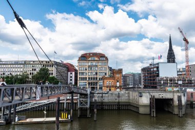 Hamburg, Almanya - 21 Ağustos 2019: Arka planda Aziz Nikolay Kilisesi 'nin (St. Nikolai) çan kulesi ve Almanya' nın Hamburg kentindeki insanların bulunduğu Kehrwieder 'deki bir kanalın yanındaki modern ve klasik binalar 