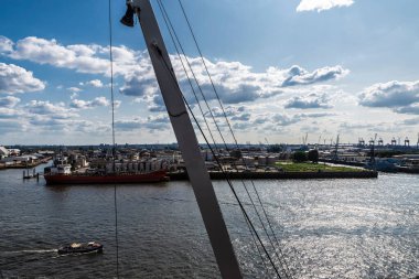 Konteynır vinçleri ve Almanya 'nın Hamburg kentindeki Elbe nehrine demirlemiş bir kargo gemisi. 