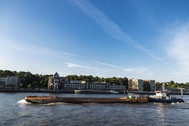 Hamburg, Almanya - 22 Ağustos 2019: Hamburg, Almanya 'da Elbe Nehri' nde bir kargo gemisi taşıyan römorkör 