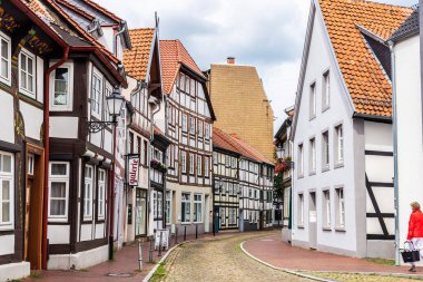 Hamelin, Almanya - 20 Ağustos 2019: Ortaçağ evleriyle dolu bir sokak Hamelin, Aşağı Saksonya, Almanya 'da yürüyen bir kadın