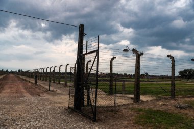 Auschwitz, Polonya - 30 Ağustos 2018: Günbatımında Auschwitz Birkenau toplama kampının elektrikli çiti, 2. Dünya Savaşı sırasında Nazi Almanyası tarafından işletilen bir imha kampı ve Polonya 'nın Krakow kenti yakınlarındaki Yahudi soykırımı 