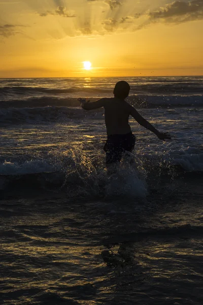 Niño bañándose en la playa al atardecer —  Fotos de Stock