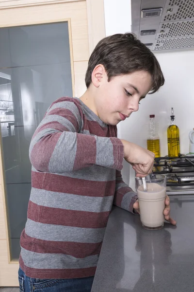 Młody chłopak przygotowuje szklankę mleka — Zdjęcie stockowe