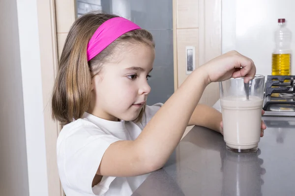 Girl förbereder ett glas mjölk — Stockfoto