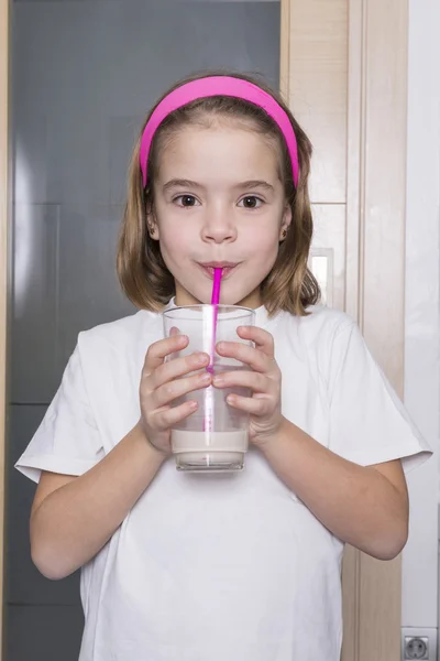Malá holčička pije sklenici mléka — Stock fotografie