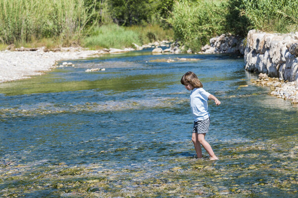 Little girl crossing a river 