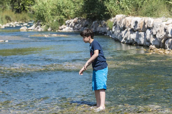 Мальчик, переходящий реку — стоковое фото