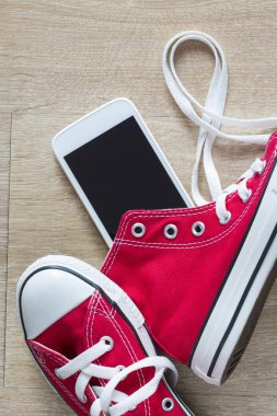 Bir çift kırmızı spor ayakkabılar ve bir akıllı telefon