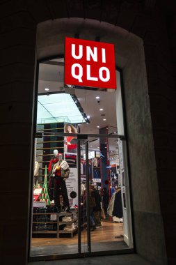 Barselona, İspanya - 25 Kasım 2025: Barcelona, Katalonya, İspanya 'da bir alışveriş caddesinde geceleyin Uniqlo giyim mağazasının imzası