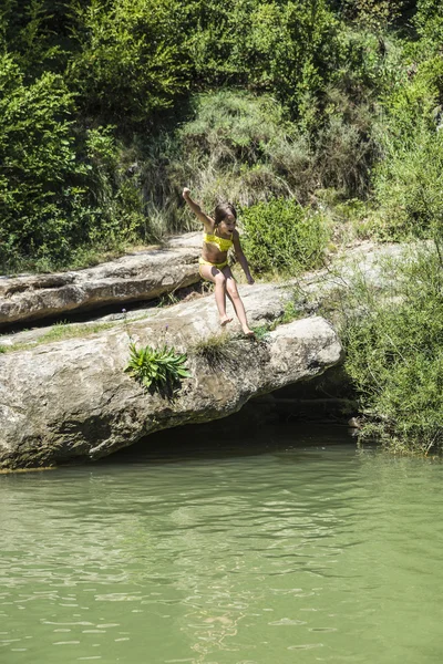 Bambina che salta in un fiume — Foto Stock